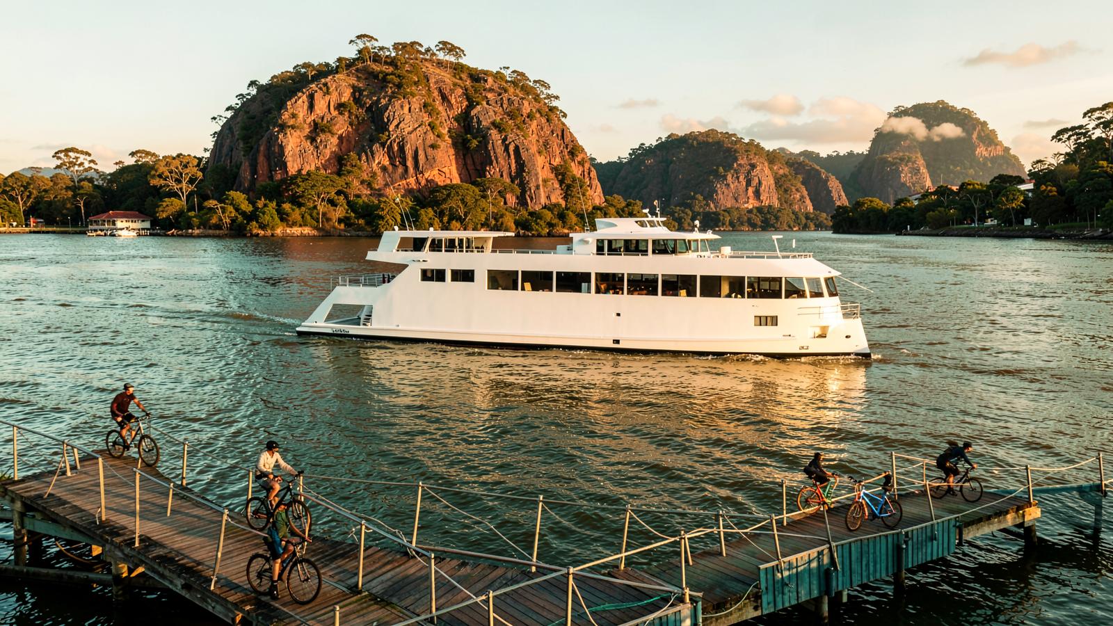 A CityCat ferry on the Brisbane River with cyclists on the inner-east riverwalk